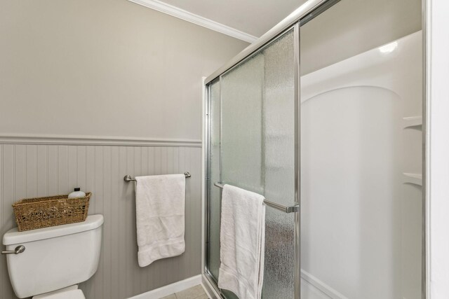 full bath with a stall shower, a wainscoted wall, crown molding, and toilet