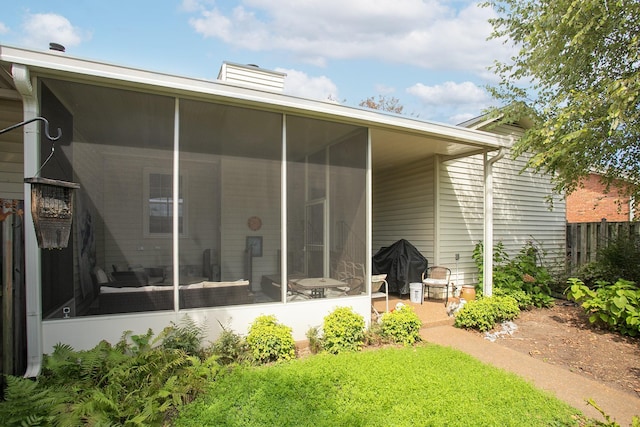 back of property with a chimney, fence, and a sunroom