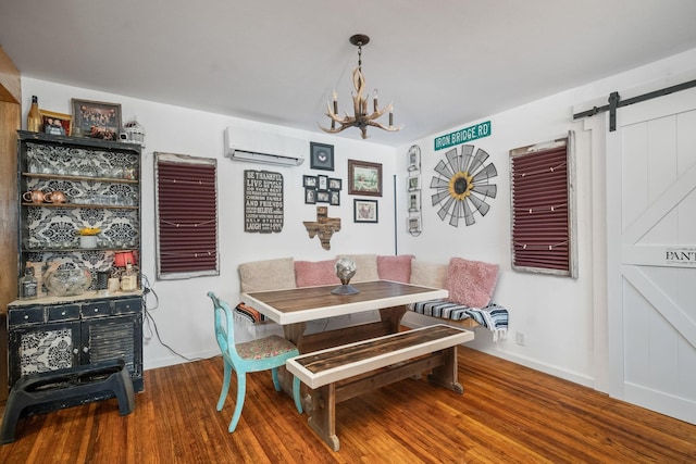 dining room featuring a barn door, a wall unit AC, a notable chandelier, wood finished floors, and baseboards