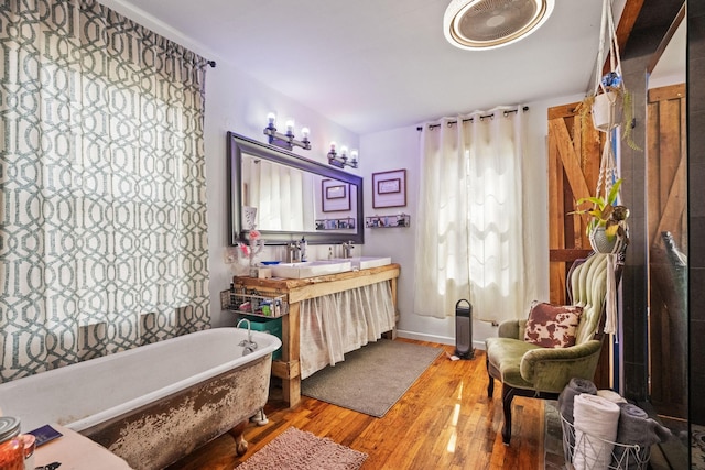 full bath with a freestanding tub, wood finished floors, and vanity