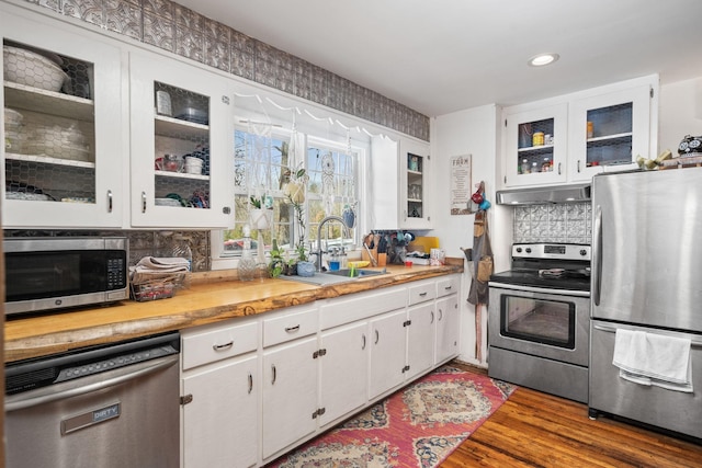 kitchen featuring stainless steel appliances, light countertops, backsplash, a sink, and under cabinet range hood