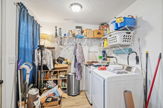 washroom with a textured ceiling, laundry area, washing machine and clothes dryer, and light wood-style floors