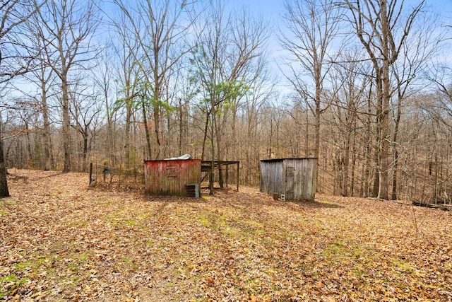 view of yard featuring an outbuilding, a shed, and a wooded view