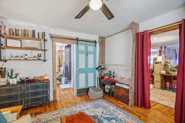 interior space with a closet, wood finished floors, ceiling fan, and a barn door