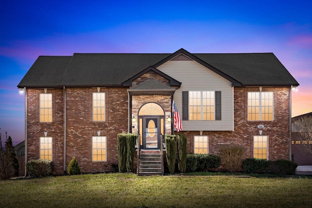 view of front of house featuring brick siding and a lawn