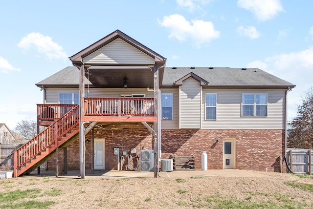 back of property featuring a lawn, a patio, stairs, central air condition unit, and brick siding