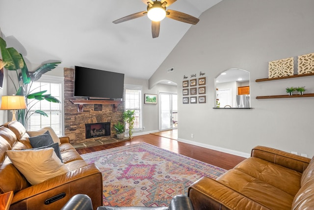 living area featuring arched walkways, a fireplace, baseboards, and wood finished floors