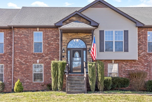 view of front of house featuring brick siding and roof with shingles