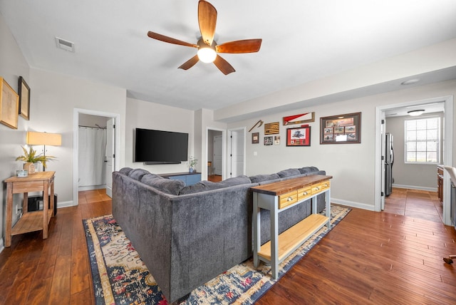 living room featuring baseboards, visible vents, dark wood finished floors, and a ceiling fan