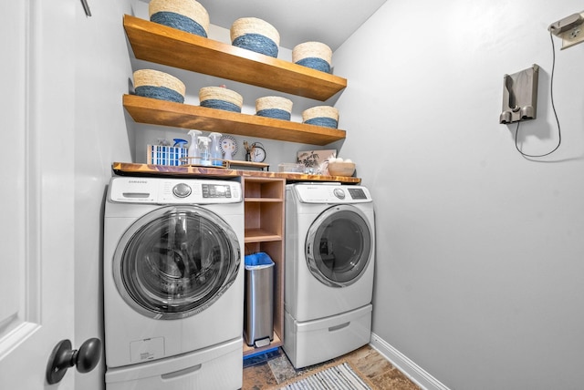 clothes washing area with laundry area, washing machine and dryer, and baseboards