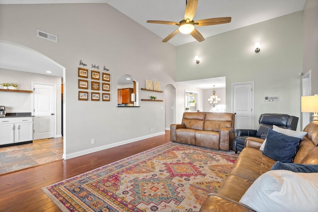 living room featuring arched walkways, light wood finished floors, visible vents, baseboards, and ceiling fan with notable chandelier