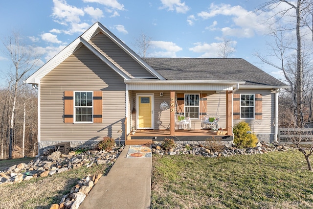 view of front of property featuring covered porch, roof with shingles, and a front lawn