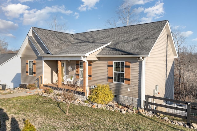 view of front of house featuring a porch, a front yard, roof with shingles, and fence