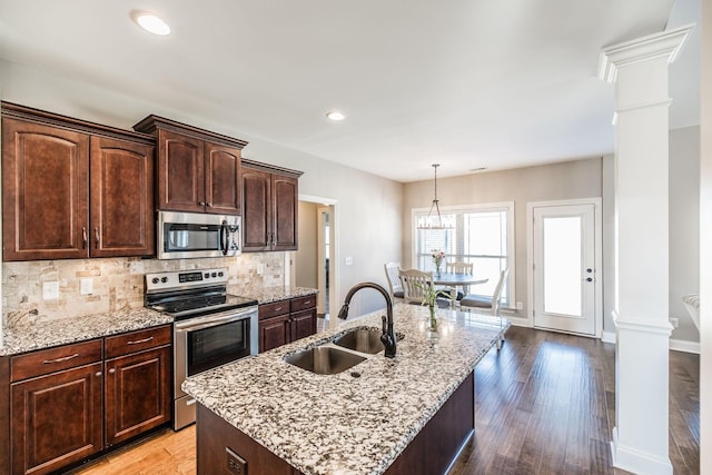 kitchen with backsplash, decorative columns, stainless steel appliances, and a sink