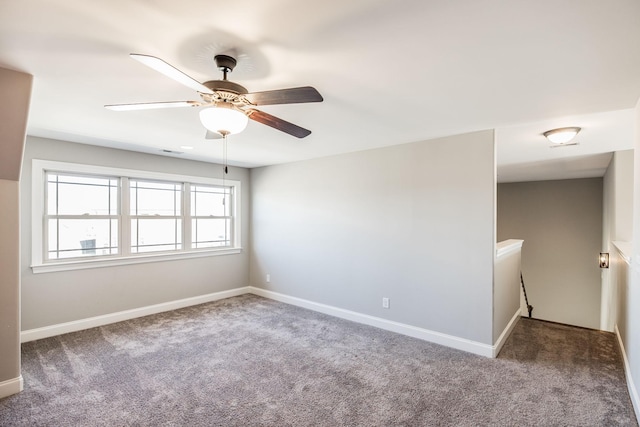 carpeted spare room with ceiling fan and baseboards