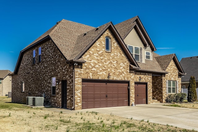 view of front of home with central AC, brick siding, roof with shingles, and concrete driveway