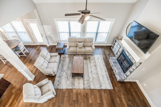 living room with ceiling fan, a fireplace, baseboards, and wood finished floors