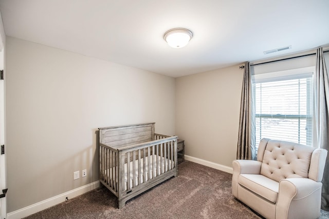 carpeted bedroom featuring a crib, visible vents, and baseboards