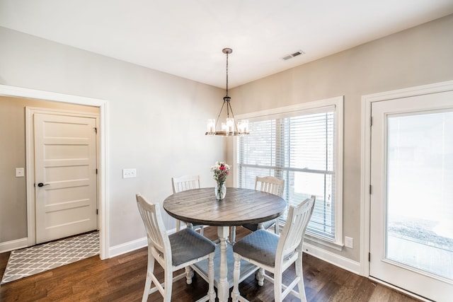 dining space with dark wood-style floors, baseboards, visible vents, and a chandelier