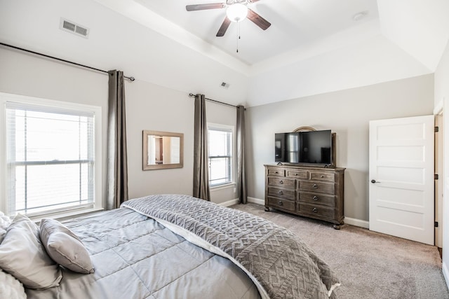 carpeted bedroom featuring baseboards, visible vents, a ceiling fan, lofted ceiling, and a tray ceiling