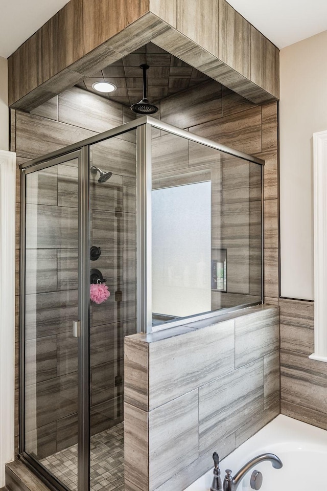 bathroom with a stall shower and a garden tub