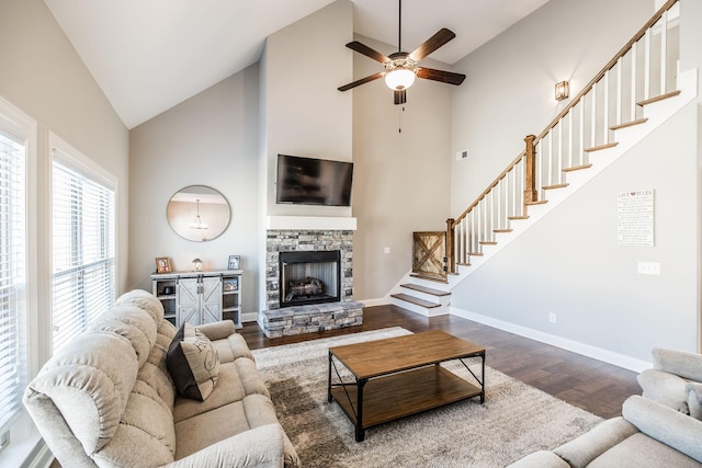 living room featuring a fireplace, stairway, ceiling fan, wood finished floors, and baseboards