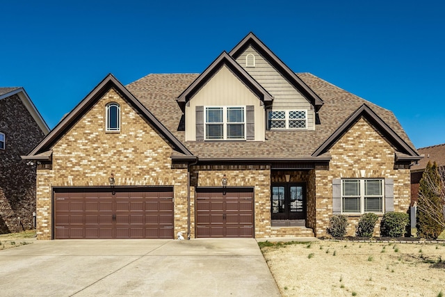 craftsman house with brick siding, french doors, concrete driveway, and roof with shingles