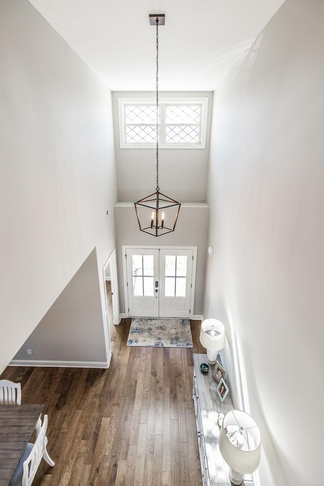 foyer featuring a healthy amount of sunlight, a chandelier, dark wood finished floors, and french doors