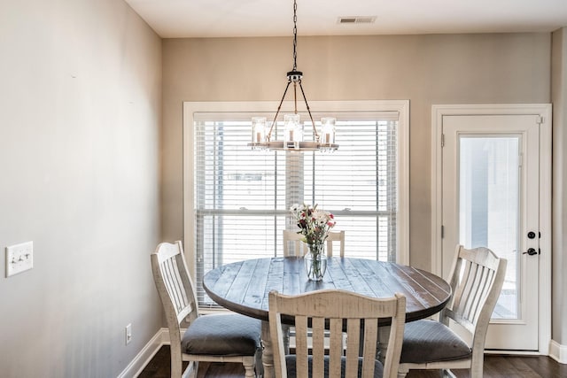 dining area featuring dark wood-style flooring, visible vents, baseboards, and an inviting chandelier