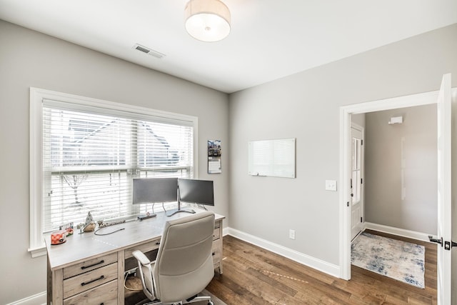 office area with wood finished floors, visible vents, and baseboards