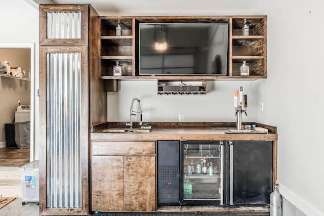 bar featuring wine cooler, baseboards, indoor wet bar, and a sink