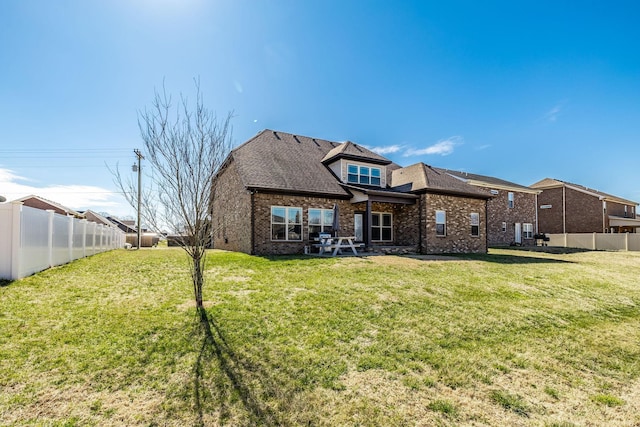 back of house featuring a fenced backyard, a yard, and brick siding