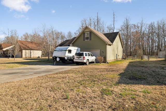 view of home's exterior featuring a lawn, driveway, and fence