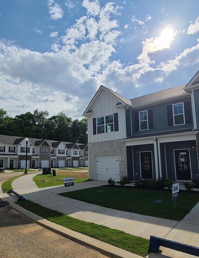 multi unit property featuring board and batten siding, a front yard, a residential view, and an attached garage