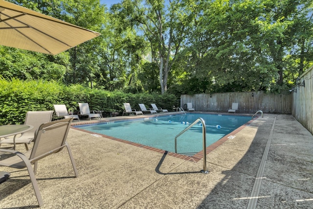 community pool with a patio area and a fenced backyard