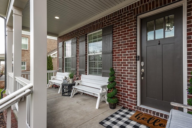 property entrance with a porch and brick siding