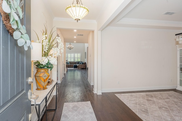 foyer entrance featuring baseboards, crown molding, wood finished floors, and visible vents
