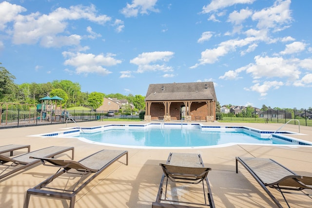 pool featuring a patio area, a playground, and fence
