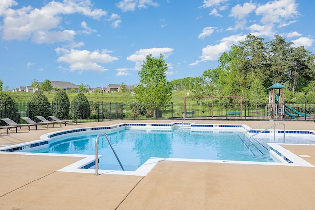 community pool featuring fence, playground community, and a patio