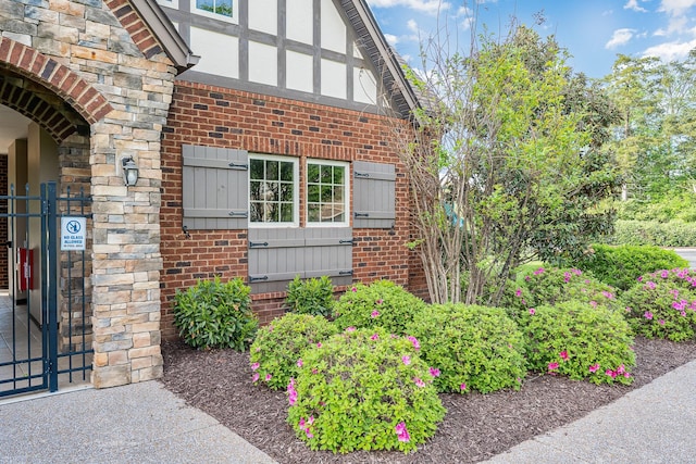 property entrance featuring a gate, brick siding, and stone siding
