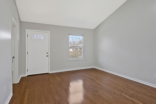 foyer with dark wood-type flooring, vaulted ceiling, and baseboards