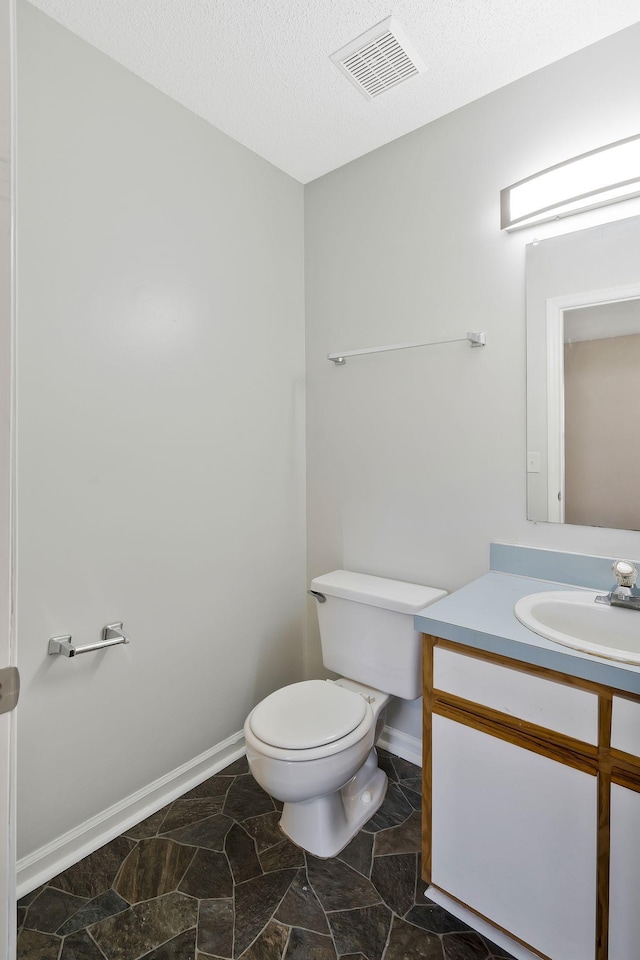 bathroom with visible vents, toilet, a textured ceiling, vanity, and baseboards