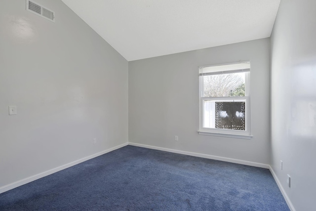 spare room with dark carpet, baseboards, visible vents, and vaulted ceiling