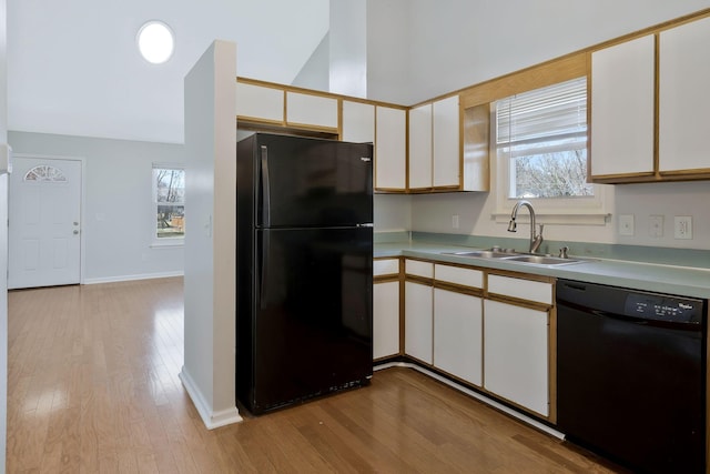 kitchen featuring black appliances, a sink, white cabinetry, and light wood-style floors