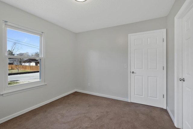 unfurnished room featuring carpet and baseboards