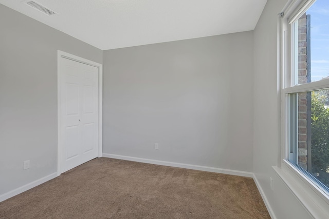 spare room with carpet, visible vents, and baseboards