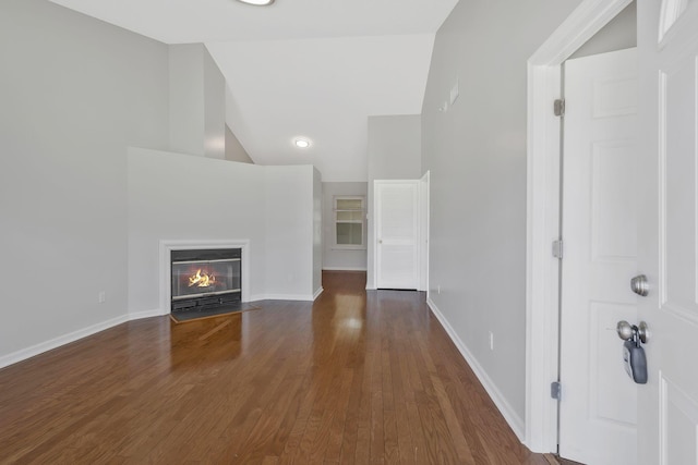 unfurnished living room featuring a fireplace with flush hearth, high vaulted ceiling, baseboards, and wood finished floors