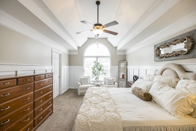 bedroom featuring lofted ceiling, a ceiling fan, ornamental molding, wainscoting, and light carpet