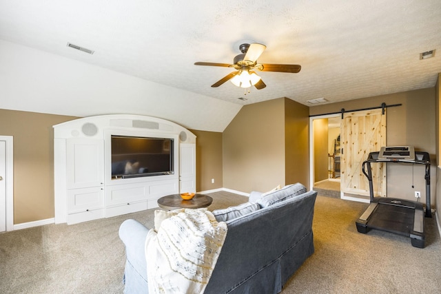 living room with a barn door, carpet floors, visible vents, a ceiling fan, and vaulted ceiling