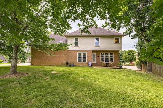 back of house featuring brick siding, a patio, fence, and a lawn